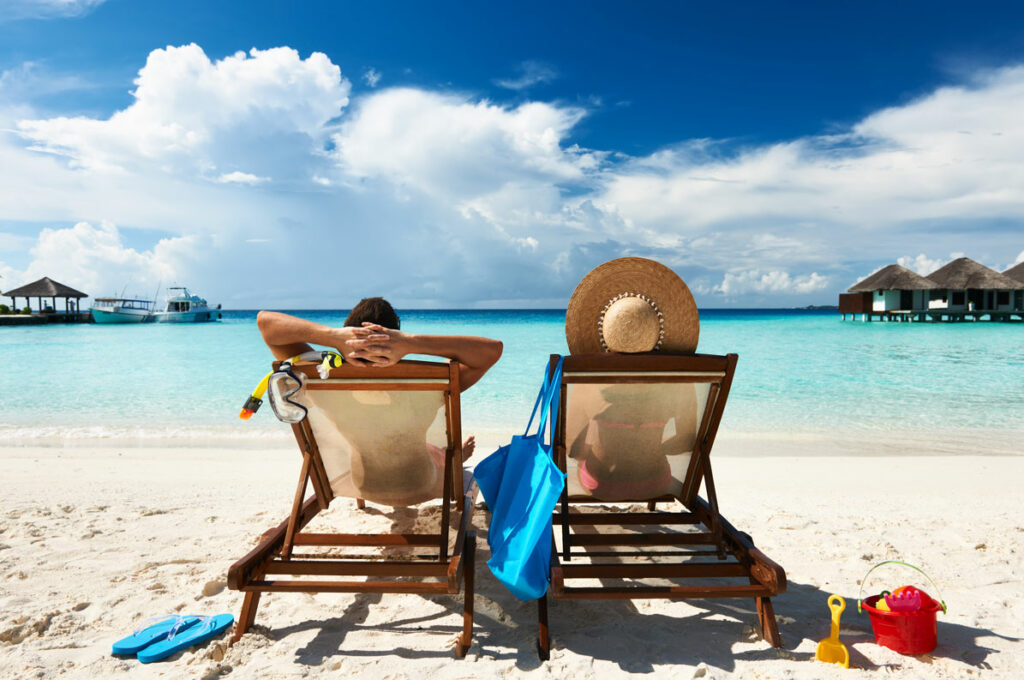 couple sitting in beach chairs on a tropical beach