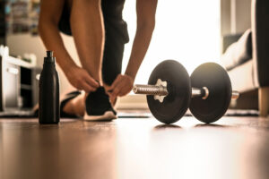 person tying shoe next to barbell